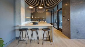 A modern kitchen with a central island, three stools, pendant lighting, and a large window. - Hyve-Anthem-Private Balconies-Walk to Broadway (Nashville)