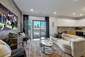 A modern living room with a sofa, a coffee table, and a TV mounted on the wall. - Hyve-Anthem-Private Balconies-Walk to Broadway (Nashville)