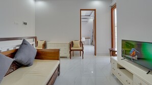 A modern living room with a bed, a TV, a desk, and a chair. - Sedana Villa Sanur (Denpasar)