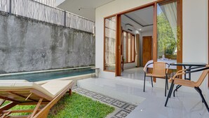 A modern outdoor area with a pool, a lounge chair, and a table with chairs. - Sedana Villa Sanur (Denpasar)