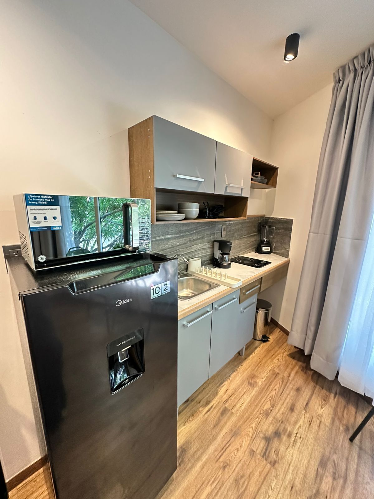 A compact kitchen with a built-in refrigerator, a coffee maker, and a microwave.
