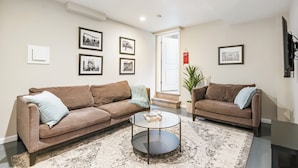 Un salon avec deux canapés marron, une table basse ronde et un tapis à motifs.