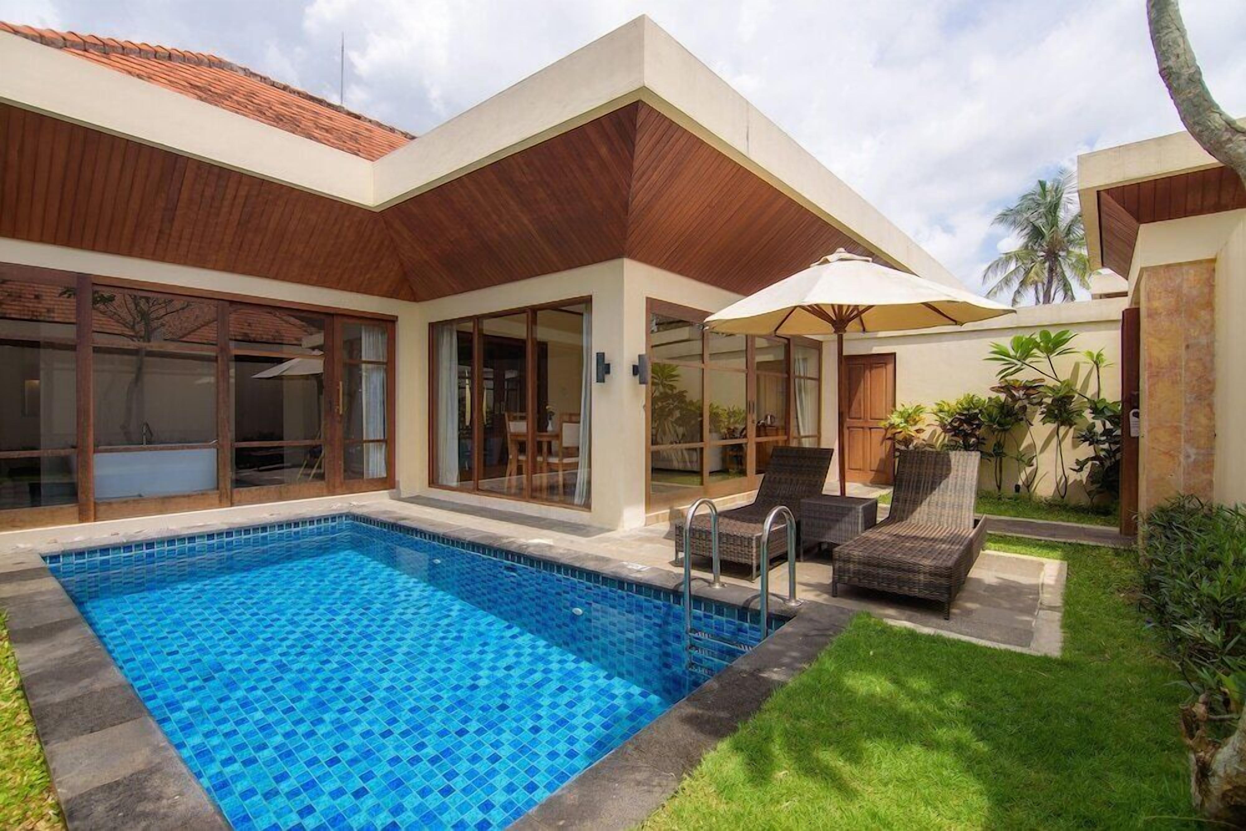 Una moderna casa con piscina, ampie finestre e mobili da esterno.
