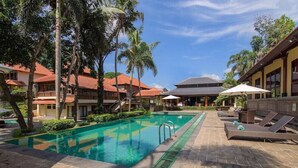 A swimming pool with a clear blue water, surrounded by palm trees and lounge chairs. - Champlung Sari Villa & Spa (Ubud)