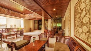 A spacious lobby with wooden furniture, a large wall mural, and a seating area with a bench and a sofa. - Champlung Sari Villa & Spa (Ubud)