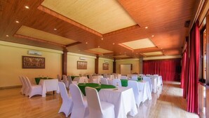 A conference room with multiple tables and chairs, wooden ceiling, and red curtains. - Champlung Sari Villa & Spa (Ubud)