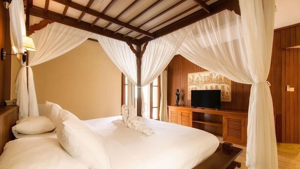 A bed with white linens, a wooden headboard, and a canopy. - Champlung Sari Villa & Spa (Ubud)
