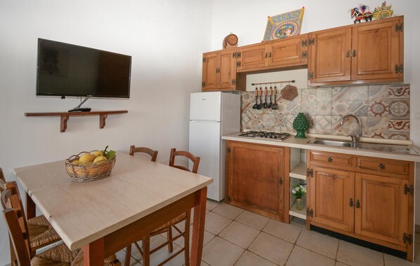 A kitchen with wooden cabinets, a white refrigerator, a stove, and a tiled backsplash.