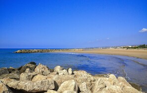 A rocky shoreline with a clear blue sky.
