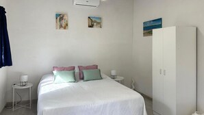 Un dormitorio con cama, dos mesitas de noche, un armario y decoración en la pared.