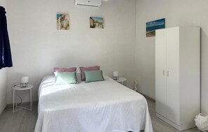 Ein Schlafzimmer mit einem Bett, zwei Nachttischen, einem Kleiderschrank und Wandbildern.