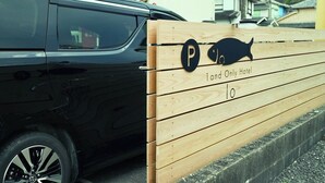 A car parked next to a wooden fence with a parking sign and a fish symbol. - 1 and Only Hotel Io (Minamiise)