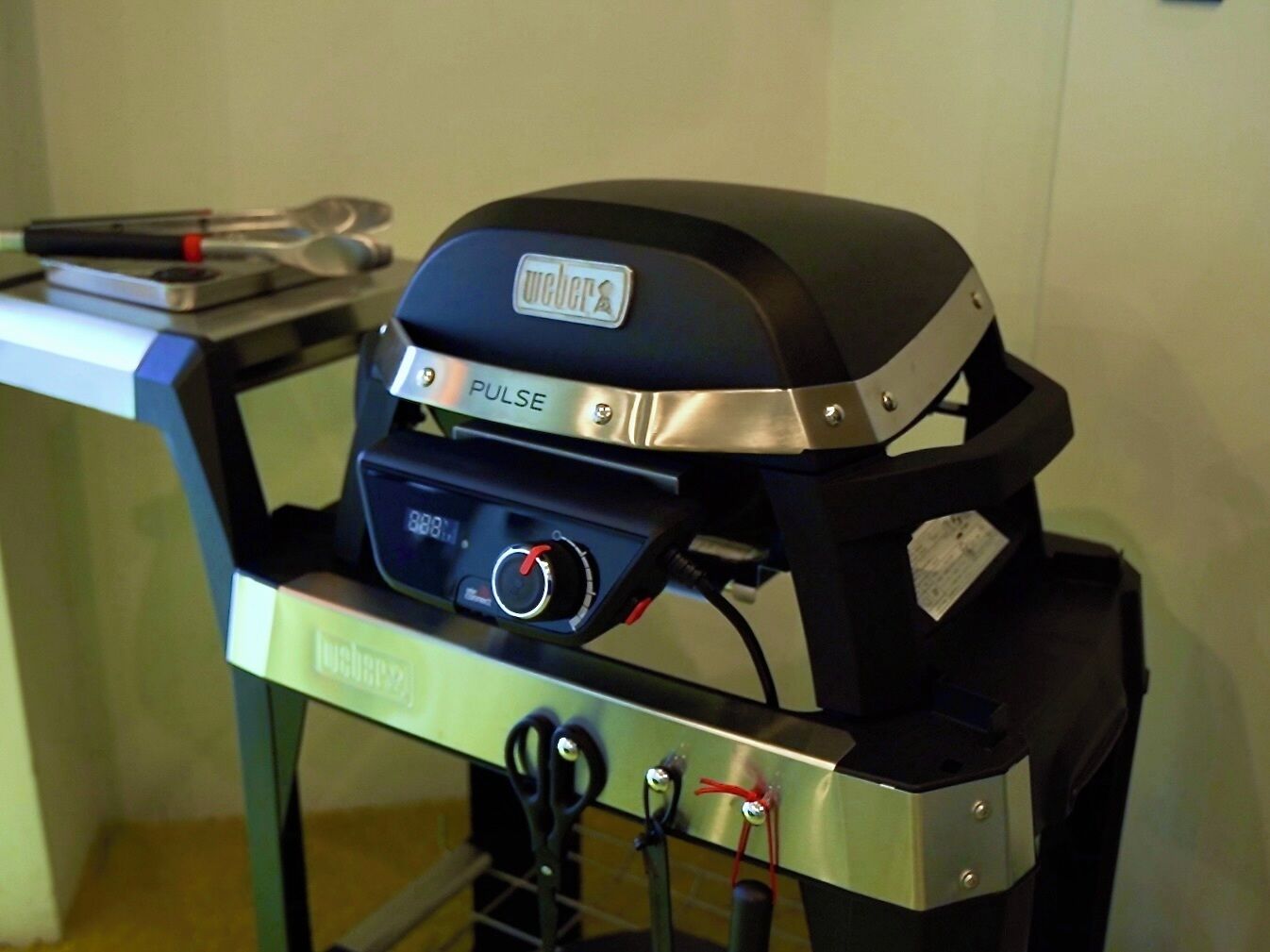 Un barbecue Weber Pulse doté d’un écran numérique, de boutons de commande et d’une poignée.