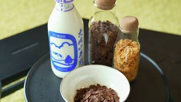 A bottle of milk, two glass containers with brown caps, and a bowl of cereal on a tray.