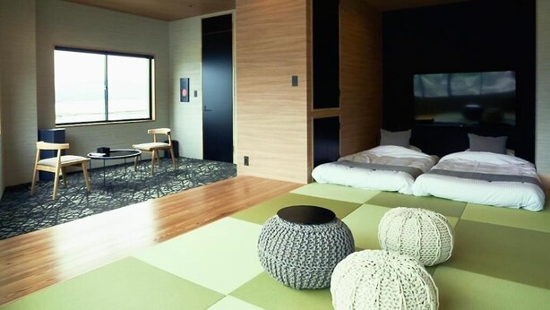 A modern hotel room with a large bed, a seating area with chairs, a small table, and a large window. - 1 and Only Hotel Io (Minamiise)