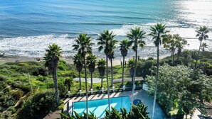 A pool area with a view of the ocean and palm trees. - Beautiful Home above Mesa Bluffs (Santa Barbara)