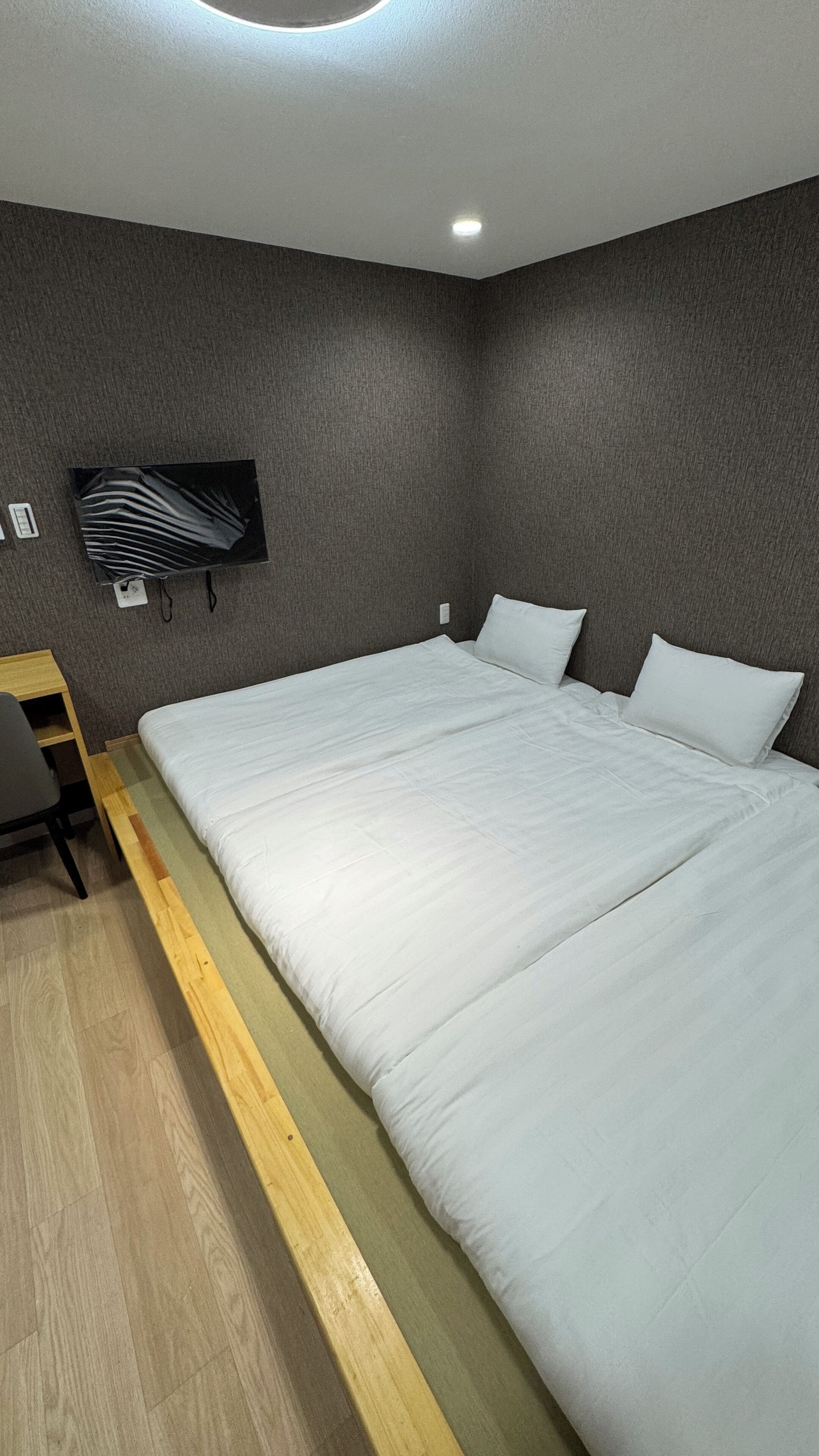 Una habitación de hotel moderna con una cama grande, un escritorio y un televisor de pantalla plana montado en la pared.