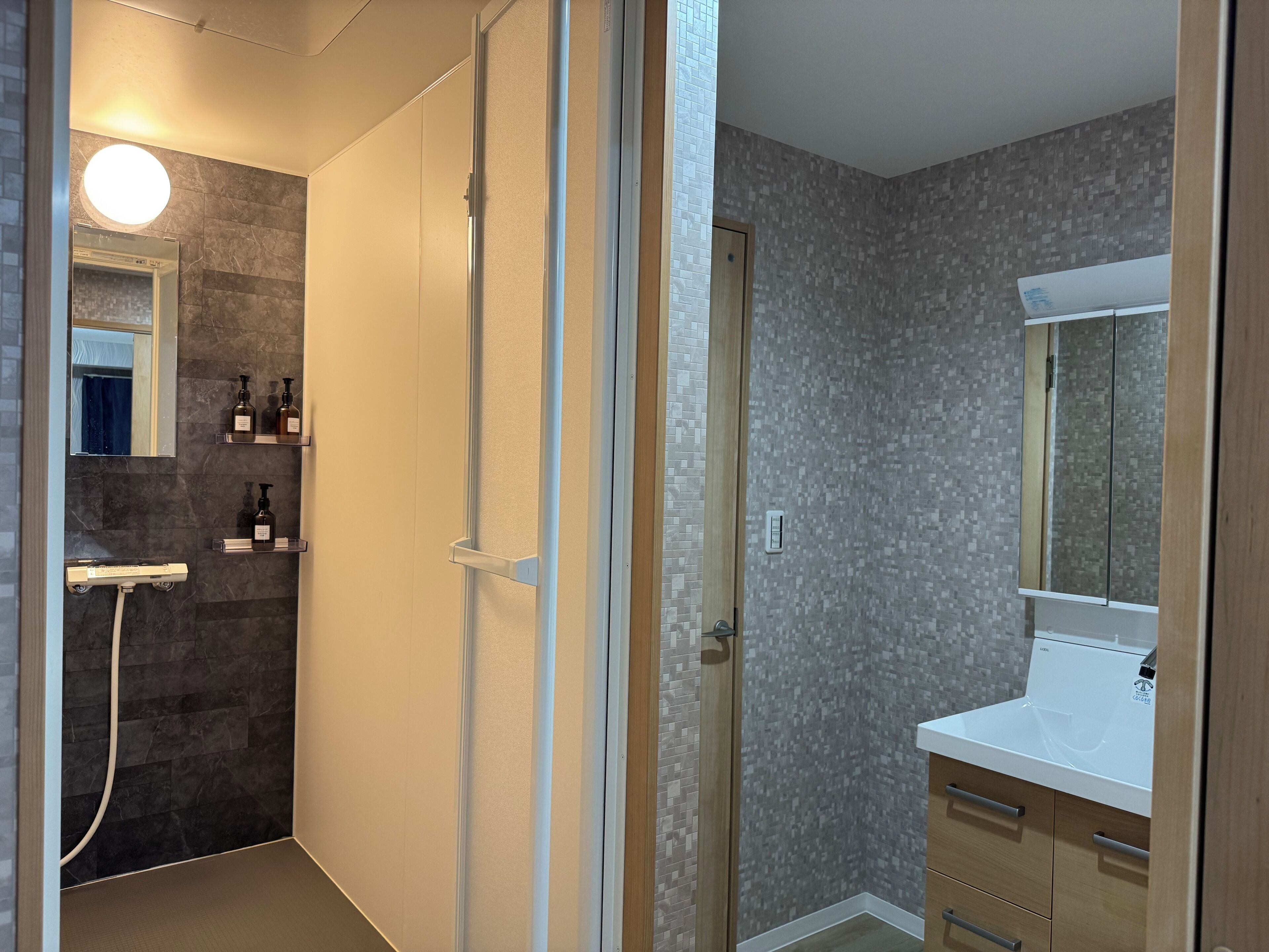 A bathroom with a shower, a mirror, and a sink.