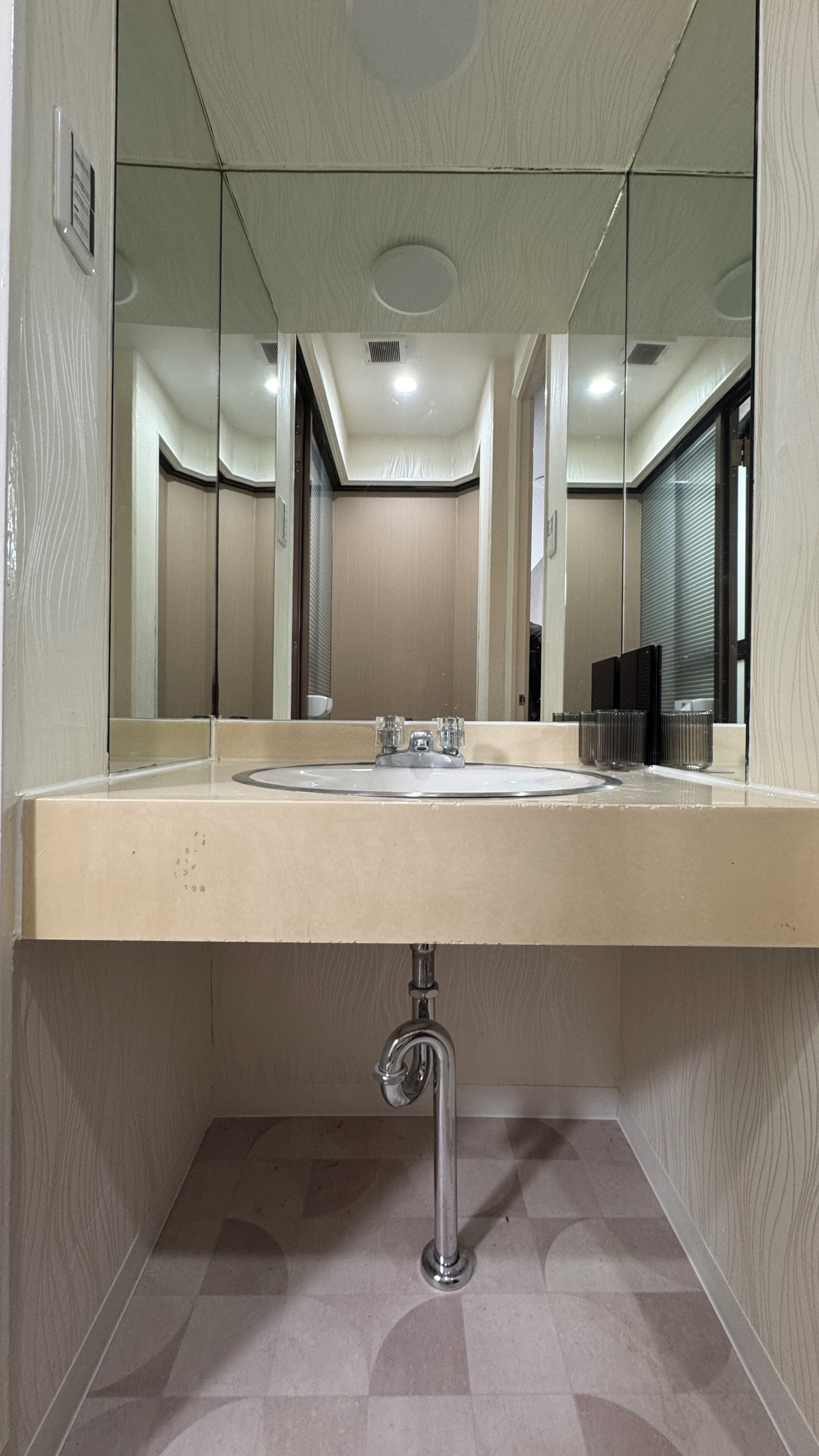A bathroom with a large mirror, a sink, and a toilet.