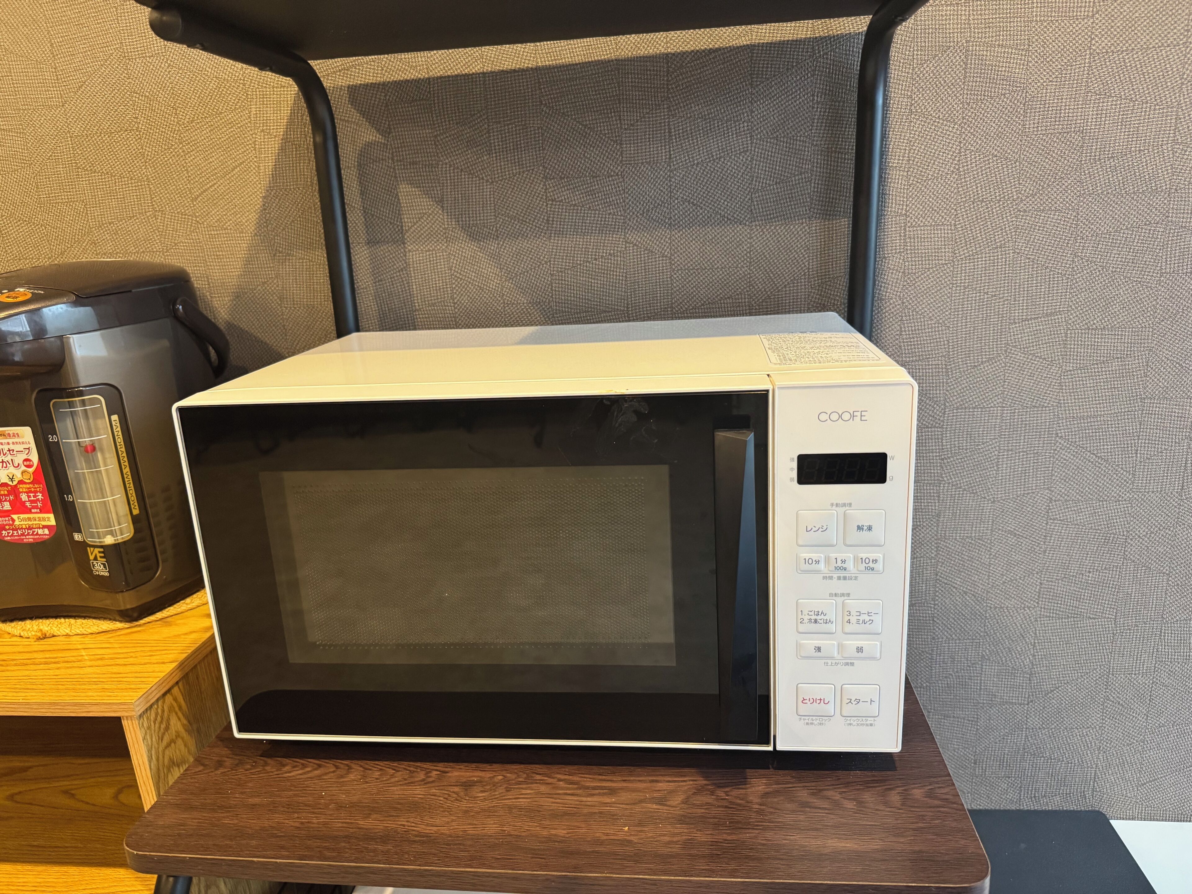 A white microwave oven with a digital display and control buttons on a wooden table.