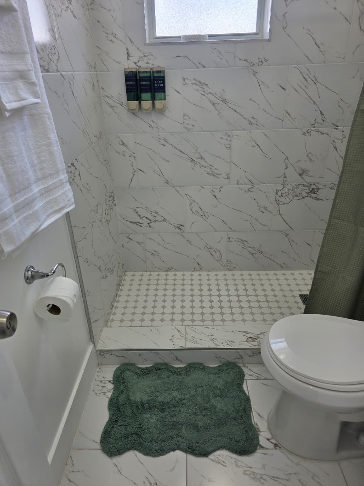 Un bagno con il water, una doccia e un portasciugamani.