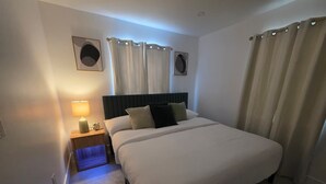 Ein Hotelzimmer mit einem großen Bett, einem Nachttisch mit Lampe und zwei Wanduhren.