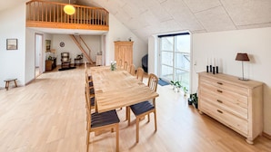 A spacious dining area with a long wooden table and chairs, a staircase leading to an upper level, and a large window providing natural light. - Amazing apartment in Nørre Nebel (Nørre Nebel)