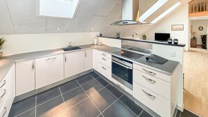 A modern kitchen with white cabinets, a black countertop, and a skylight. - Amazing apartment in Nørre Nebel (Nørre Nebel)