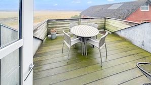 A wooden deck with a round table and wicker chairs, overlooking a field. - Amazing apartment in Nørre Nebel (Nørre Nebel)