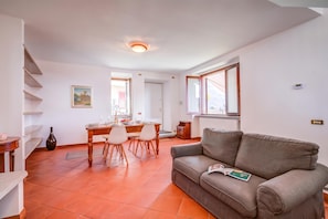 Un comedor con una mesa de madera dispuesta para cuatro personas, un sofá gris y un cuadro en la pared.