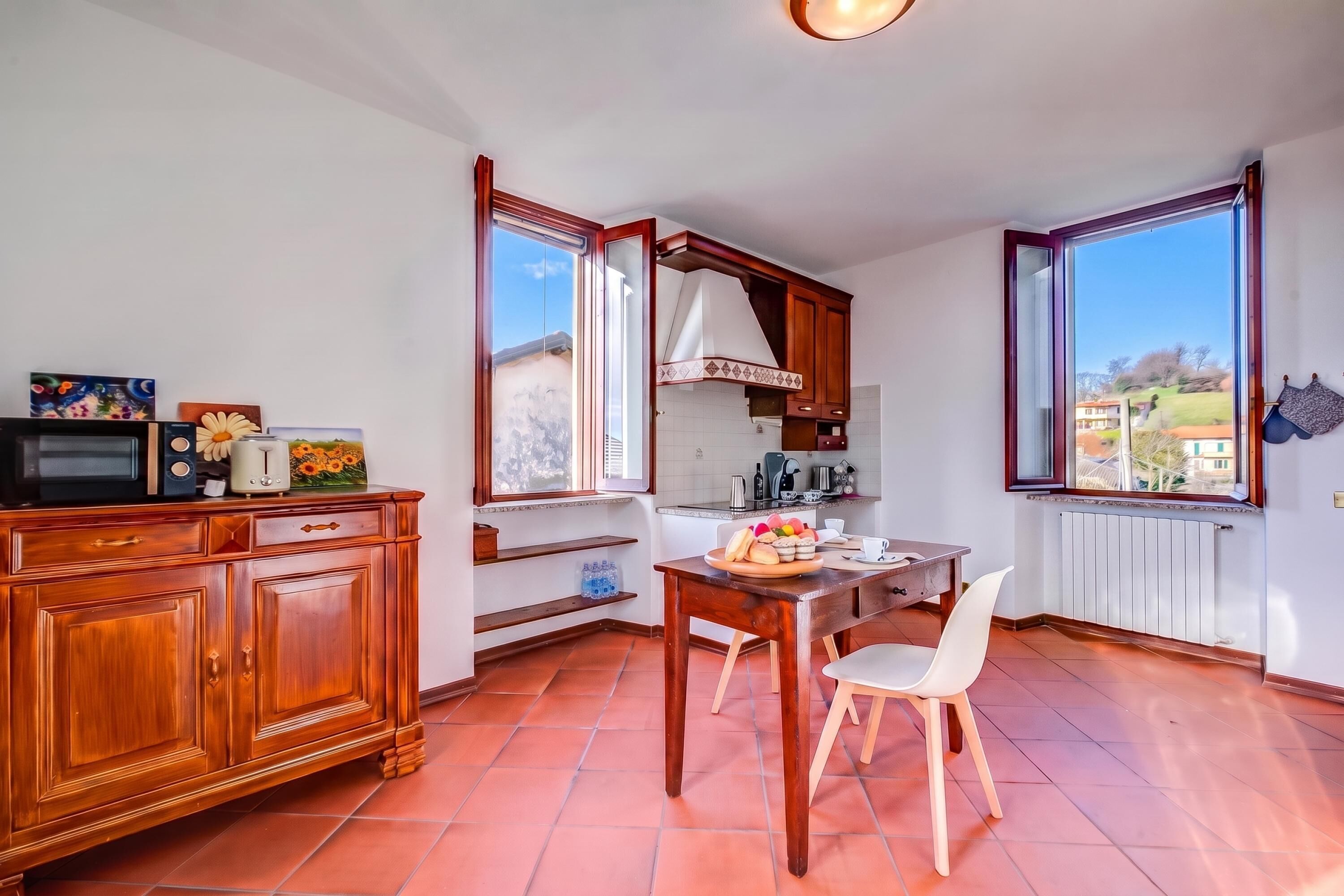 Une cuisine avec des meubles en bois, une table à manger avec des chaises, un four à micro-ondes et une fenêtre donnant sur l’extérieur.