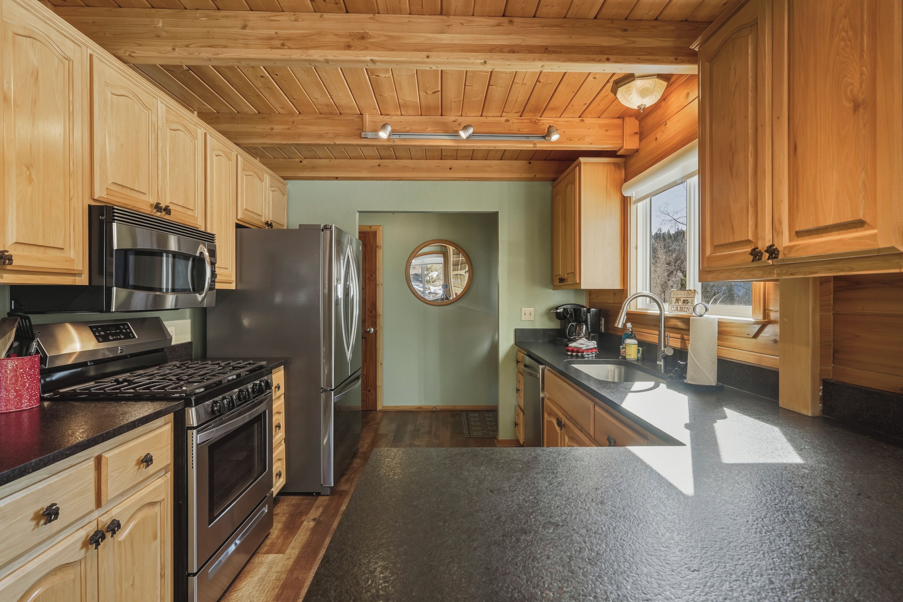 A modern kitchen with wooden cabinets, stainless steel appliances, and a black countertop.