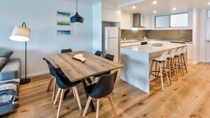 A modern kitchen with white cabinets, a marble island, and bar stools. - Frangipani Lodge 101 (Hamilton Island)