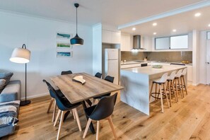 Une cuisine moderne avec des meubles blancs, un îlot en marbre et des tabourets de bar.