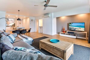 Ein modernes Wohnzimmer mit Sofa, Couchtisch, Fernseher und Essbereich.