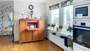 Eine Küche mit Holzausstattung, einem Bosch-Backofen und einem Fenster mit blumigem Vorhang.