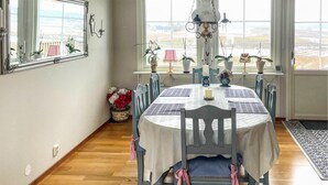 Ein Esszimmer mit rundem Tisch, Stühlen, einer Chandelüster und Topfpflanzen.
