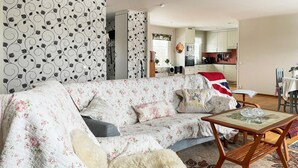 Ein Wohnzimmer mit einem blumigen Sofa, einem Holztisch und floraler Tapete.