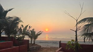 Escena de playa con palmeras y un atardecer.