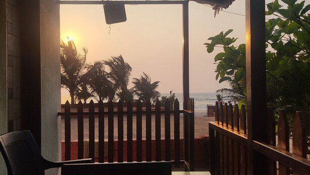 Un espacio de estar al aire libre cubierto con vista a la playa y palmeras.