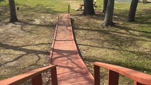 Un camino de madera que lleva a un muelle junto a un lago, rodeado de árboles.