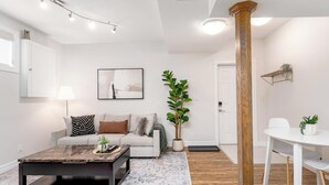 Ein modernes Wohnzimmer mit einer Couch, einem Couchtisch und einer großen Pflanze.