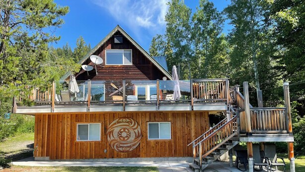 A wooden cabin with a deck, a staircase, and a large window.