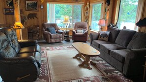 A cozy cabin interior with leather sofas, a wooden coffee table, and a rug with animal prints.