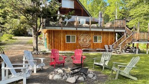 A cabin with a deck, outdoor seating, and a fire pit.