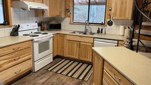 A kitchen with wooden cabinets, a stove, a microwave, and a sink.