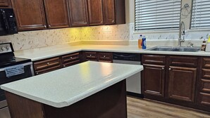 Una cocina moderna con armarios de madera, encimera de granito y lavavajillas integrado.