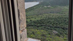 Vista desde una ventana sobre un valle con montañas, un lago y edificios dispersos.