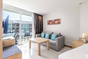 Ett modernt hotellrum med en soffa, ett litet bord, en säng och ett skrivbord med en stol.