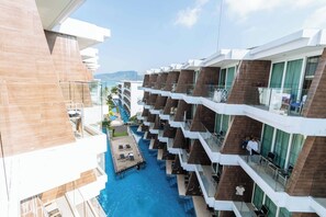 Ett hotell med flera våningar, en central pool, balkonger med glasräcken och utsikt över det omgivande landskapet.